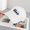 Gros plan sur la broderie bleue 'Tennis' d'une casquette en coton blanc cassé - Réglable / Blanc Cassé