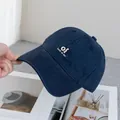 Close-up of navy blue cotton baseball cap with white 'oi' embroidery on magazine background - Adjustable / Navy Blue