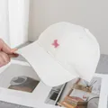 Detailed view of pink puppy embroidery on white cotton baseball cap with stylish finish - Beige