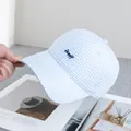 Dettaglio del cappellino a quadretti blu e bianchi con ricamo Happy su rivista aperta - Regolabile / Azzurro