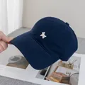 Detailed embroidery of a white puppy on a navy blue cotton baseball cap shown in a lifestyle view - Navy Blue
