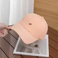 Dettaglio del cappellino da baseball corallo con ricamo S su un tavolo di legno - Regolabile / Arancione