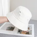 Gros plan sur le chapeau bob en coton crème avec trous déchirés et détails effilochés - Réglable / Blanc