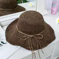 Detail of dark brown straw sun hat with wavy brim and bow next to a white dust bag - M(56-58cm) / Dark Coffee