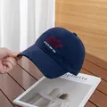Close-up of navy cotton baseball cap with red air embroidery and distressed brim detail - Adjustable / Navy Blue