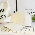 Dettaglio di un cappellino da baseball in cotone bianco crema su espositore minimalista - Beige