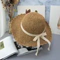 Detail of hand-woven wide brim straw hat featuring wavy edges and a delicate lace bow - Adjustable / Khaki