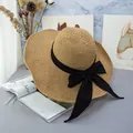 Detail of a large brim straw hat featuring a wide black ribbon and large decorative bow - Adjustable / Khaki