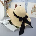 Detailed view of the woven straw hat texture with an elegant black fabric ribbon bow - Adjustable / Beige