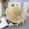 Close-up of beige woven straw sun hat with delicate lace bow and scalloped wave brim - Adjustable / Beige