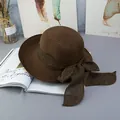 Close-up of a brown woven straw sun hat with a wide fabric bow on a minimalist background - Adjustable / Coffee