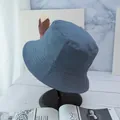 Detailed view of blue-gray cotton bucket hat stitching on a display stand with magazines - Blue Gray And Black