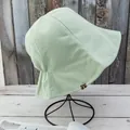 Gros plan du chapeau de soleil en coton vert clair avec étiquette et fronces au dos - Réversible / Vert+Beige