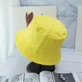 Detailed view of yellow cotton bucket hat with parallel stitching on a marble stand - Light Yellow And Black