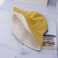 Dettaglio cappello alla pescatora giallo in cotone su tavolo in legno - Reversibile / Giallo