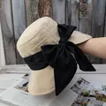 Detail van beige gevlochten zonnehoed met grote zwarte strik op een houten achtergrond - Verstelbaar / Beige