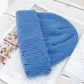 Detalle de gorro de punto azul claro con bordes desgastados sobre una revista - Azul claro