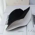 Detail view of a reversible cotton bucket hat in black and beige with premium stitching - White and Black
