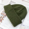Detalle de un gorro de punto verde oliva oscuro con dobladillo sobre una revista - Verde Militar