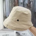Detail of beige cotton bucket hat with a metallic M badge and durable stitched brim - Adjustable / Beige