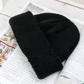Dettaglio di un berretto nero in maglia a coste su una rivista su una scrivania bianca - Stile di base / Nero