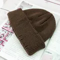 Primer plano del gorro de punto marrón mostrando la textura acanalada sobre madera - Café