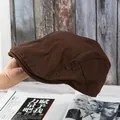 Side view of dark brown vintage cotton newsboy cap held against retro wooden background - Adjustable / Coffee