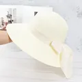 Détail d'un chapeau de paille beige tissé main avec un grand nœud et bord large - Réglable / Crème