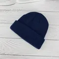 Gorro de punto azul marino con dobladillo acanalado sobre un fondo de madera minimalista - Azul marino