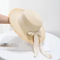 Detailopname van een beige strohoed met gerafelde randen en een sierlijke strikband - Verstelbaar / Beige Hoed Met Beige Lint