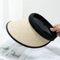 Detail of beige straw sun visor with black fabric trim held against a magazine background - Adjustable / Beige (Black Trim)