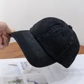 Vista detallada de la textura de mezclilla lavada y el ala rígida de una gorra negra - Ajustable / Negro
