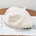 Detailed close-up of a beige wool beret featuring a rectangular metal logo plate - Adjustable / Off White