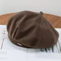 Detailed close-up of brown wool beret with silver rectangular metal logo tag - Adjustable / Coffee