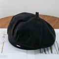 Detailed texture of black wool beret featuring a metallic rectangular logo accent - Adjustable / Black
