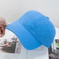 Detail of bright blue washed cotton baseball cap held by hand featuring breathable eyelets - Adjustable / Sky Blue
