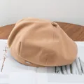 Close-up of khaki wool beret featuring a metallic brand tag on soft textured fabric - Adjustable / Khaki