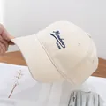 Primo piano del cappellino da baseball in cotone beige con ricamo di lettere blu scuro - Regolabile / Beige