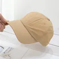 Detailed side view of a light khaki thin baseball cap held by hand on a wooden surface - Adjustable / Khaki
