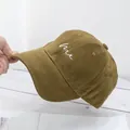 Detail shot of a mustard cotton baseball cap with white me letter embroidery - Camel