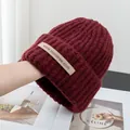 Close-up of dark red ribbed knit hat with high-quality wool blend texture and brand label - Stretchy / Burgundy