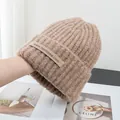 Detailed texture of khaki chunky knit wool beanie with ribbed pattern and brand label - Stretchy / Brown