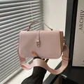 Chic pink leather square bag with gold hardware and wide shoulder strap in hand - Pink