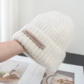 Close-up of cream wool blend knit beanie showing thick ribbed texture and brand label - Stretchy / Off White
