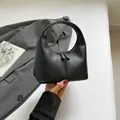 Minimalist black matte leather handbag with sleek curved handle and metallic zipper - Black