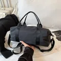 Minimalist all-black cylindrical duffel bag with woven straps and top handle for travel - Large / Black