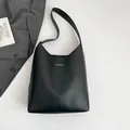 Borsa tote nera minimalista con stampa dorata posata su un blazer grigio elegante - Nero