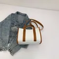 Bolso tote de lona minimalista con ribete marrón, asas de mano y una correa larga al hombro - Marrón