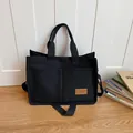 Sac cabas minimaliste en toile noire avec bandoulière réglable et grandes poches avant - Noir