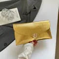 Pochette enveloppe dorée avec texture ondulée et boucle métallique géométrique - Or